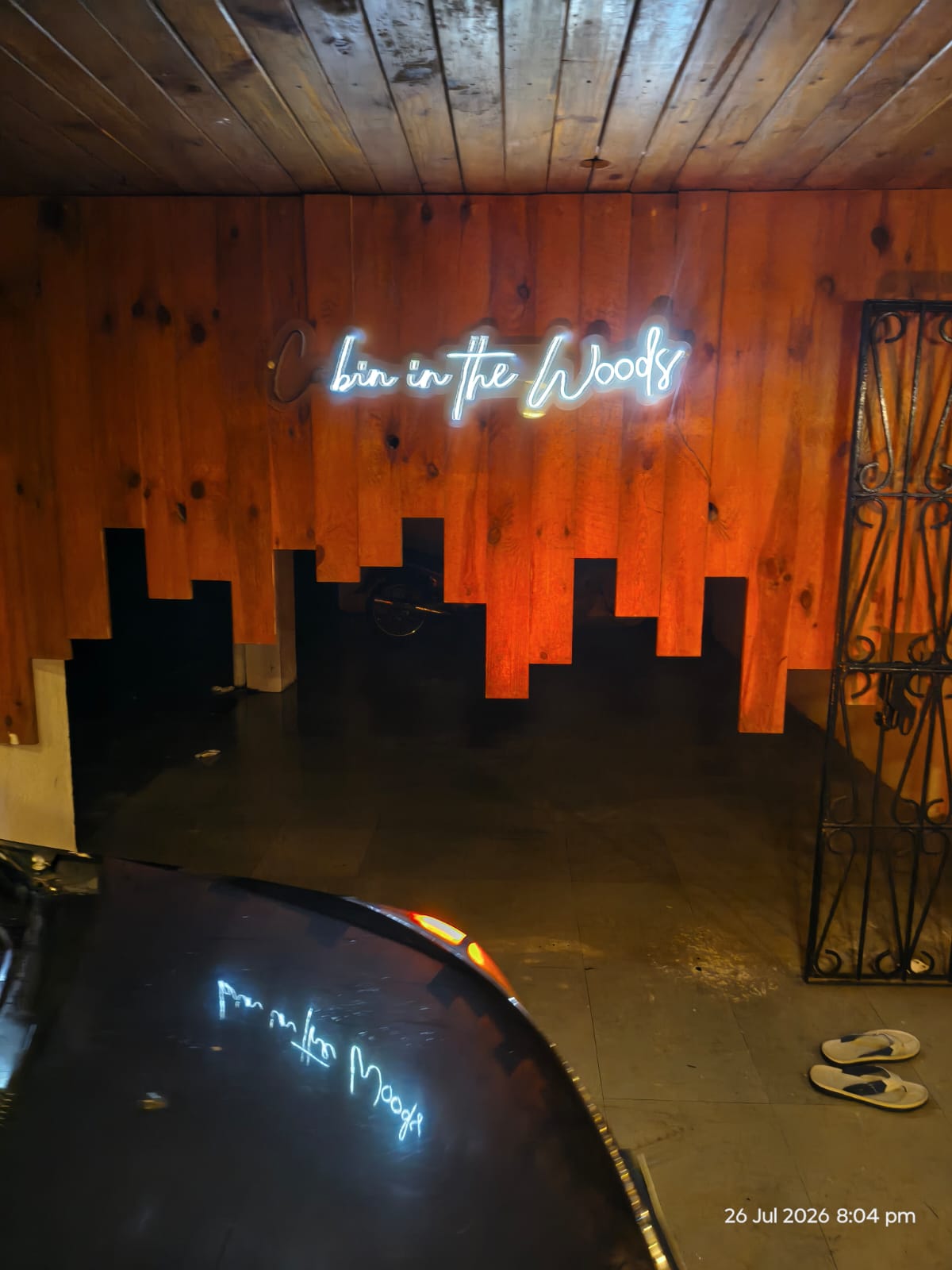 Glowing Cabin in the Woods neon sign on the cedar wall beside the pool at the Lonavala villa