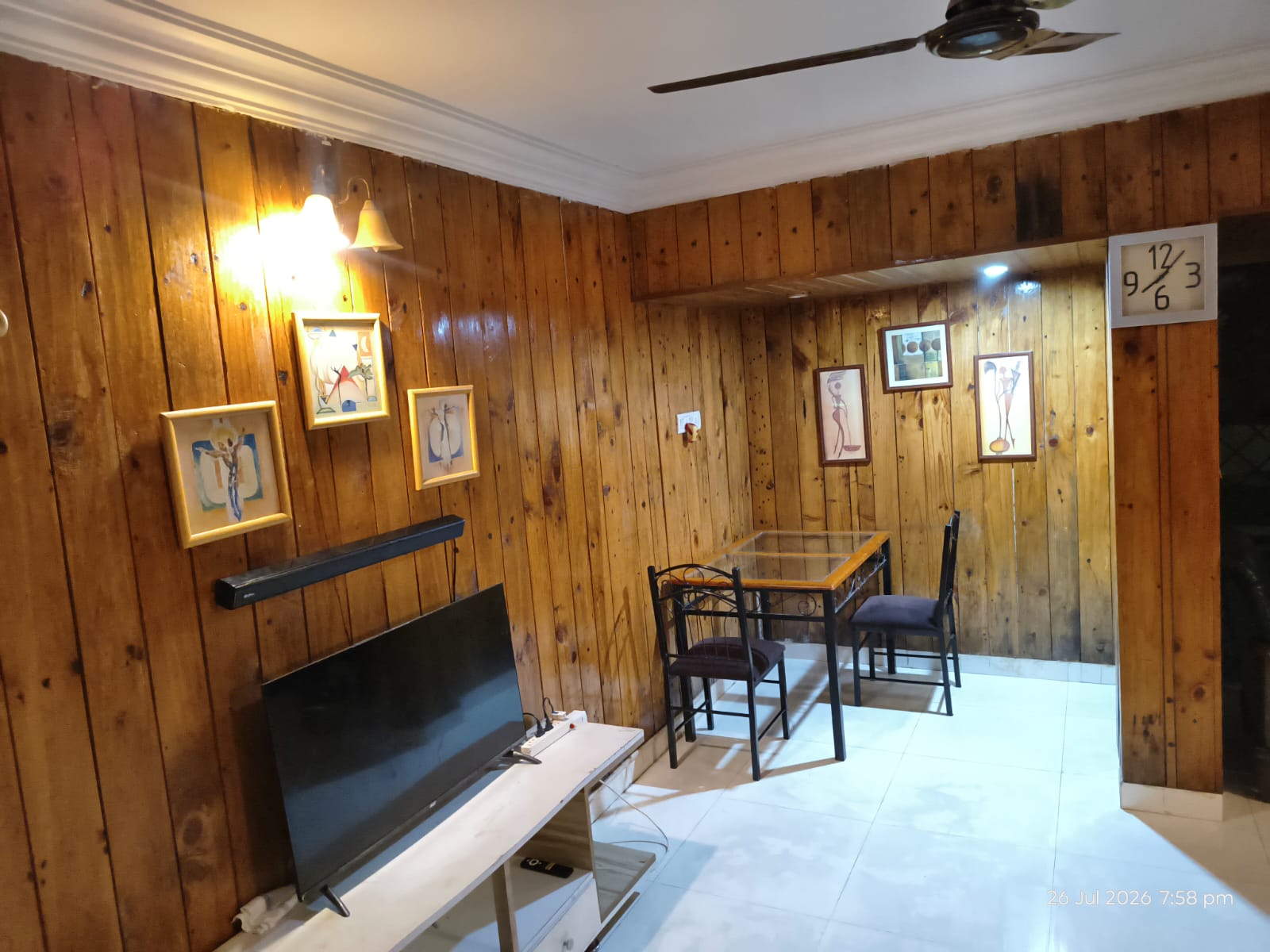 Wood-panelled living room with dining table and television at Cabin in the Woods villa, Lonavala